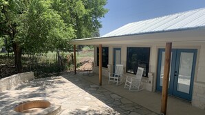 Ein überdachter Patio-Bereich mit Steinböden, einer Feuerstelle und zwei Schaukelstühlen.