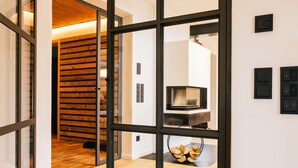 A modern interior with a wooden wall, a television, and a fireplace. - Light-flooded dream home between Chiemsee and the Alps (Traunstein)