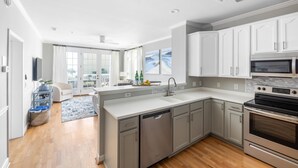 A modern kitchen with white cabinets, stainless steel appliances, and a large island with a sink. - Pet-friendly oceanfront condo steps from beach & center street (Folly Beach)
