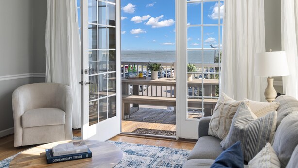 A living room with a view of the sea, a sofa, a chair, and a book on the floor. - Pet-friendly oceanfront condo steps from beach & center street (Folly Beach)