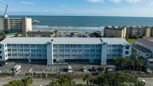 A multi-story hotel with a parking lot in front, overlooking a beach and ocean. - Pet-friendly oceanfront condo steps from beach & center street (Folly Beach)