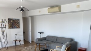 Un soggiorno moderno con un divano grigio, un tavolo da pranzo rotondo con sedie e una lampada a sospensione.