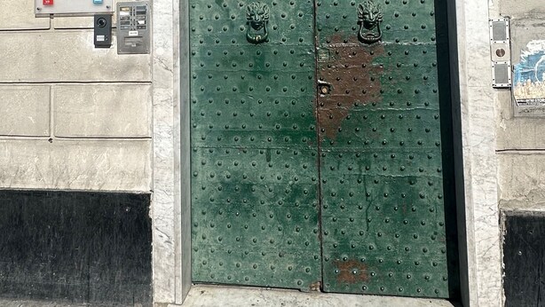 Eine grüne Doppeltür mit einem dekorativen Lüfter darüber, ein Schild für das Red and Blues Music Hotel und eine kleine Plakette an der Wand.