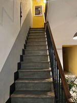Una escalera con barandilla de madera y una pared amarilla en la parte superior.
