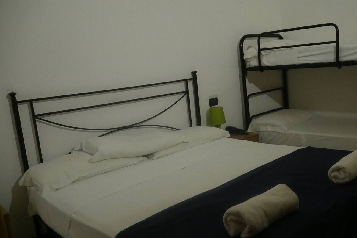 A single bed with a black metal frame, a white mattress, and a blue blanket.