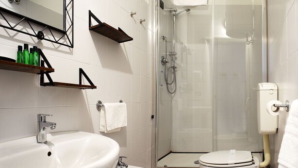 A bathroom with a sink, bidet, toilet, and a glass-enclosed shower. - RED AND BLUES MUSIC HOTEL GENOVA (Genoa)