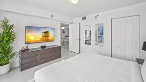 A modern bedroom with a large bed, a flat-screen TV, a dresser, and a potted plant. - The Club 3305 · *High Floor Superb Unit In the Heart Of Brickell* (Miami)