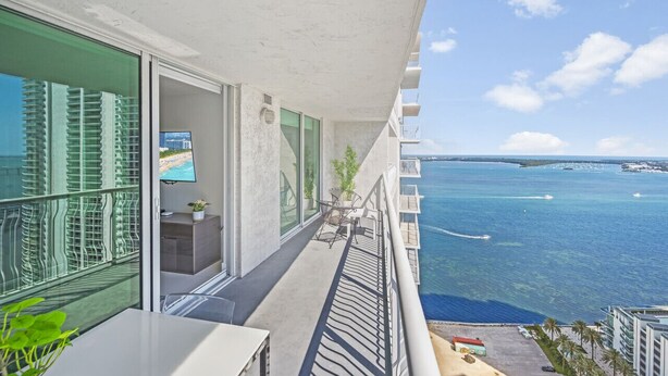 A balcony with a view of the ocean, a TV, and a small seating area. - The Club 3305 · *High Floor Superb Unit In the Heart Of Brickell* (Miami)