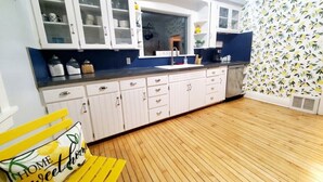A kitchen with white cabinets, a black countertop, and a wooden floor. - Spacious|Full Kitchen|Firepit|Office (Alpena)