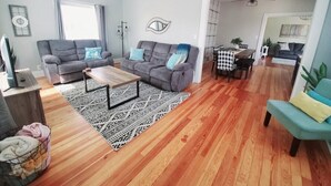 A living room with a grey sofa, a wooden coffee table, and a patterned rug. - Spacious|Full Kitchen|Firepit|Office (Alpena)