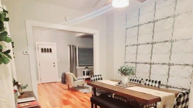 A dining area with a wooden table and chairs, a ceiling fan, and a wall with a geometric pattern. - Spacious|Full Kitchen|Firepit|Office (Alpena)