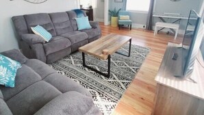 A modern living room with a grey sectional sofa, a wooden coffee table, and a TV stand. - Spacious|Full Kitchen|Firepit|Office (Alpena)