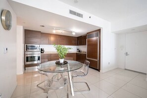 A modern kitchen with a glass dining table, stainless steel appliances, and wooden cabinets. - ICON 2901 1b DUPLICATE 2901 · ★ Iconic Icon W Unit - Pool & Ocean Views ★ (Miami)
