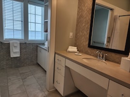 A modern bathroom with a large sink, mirror, and towel rack.