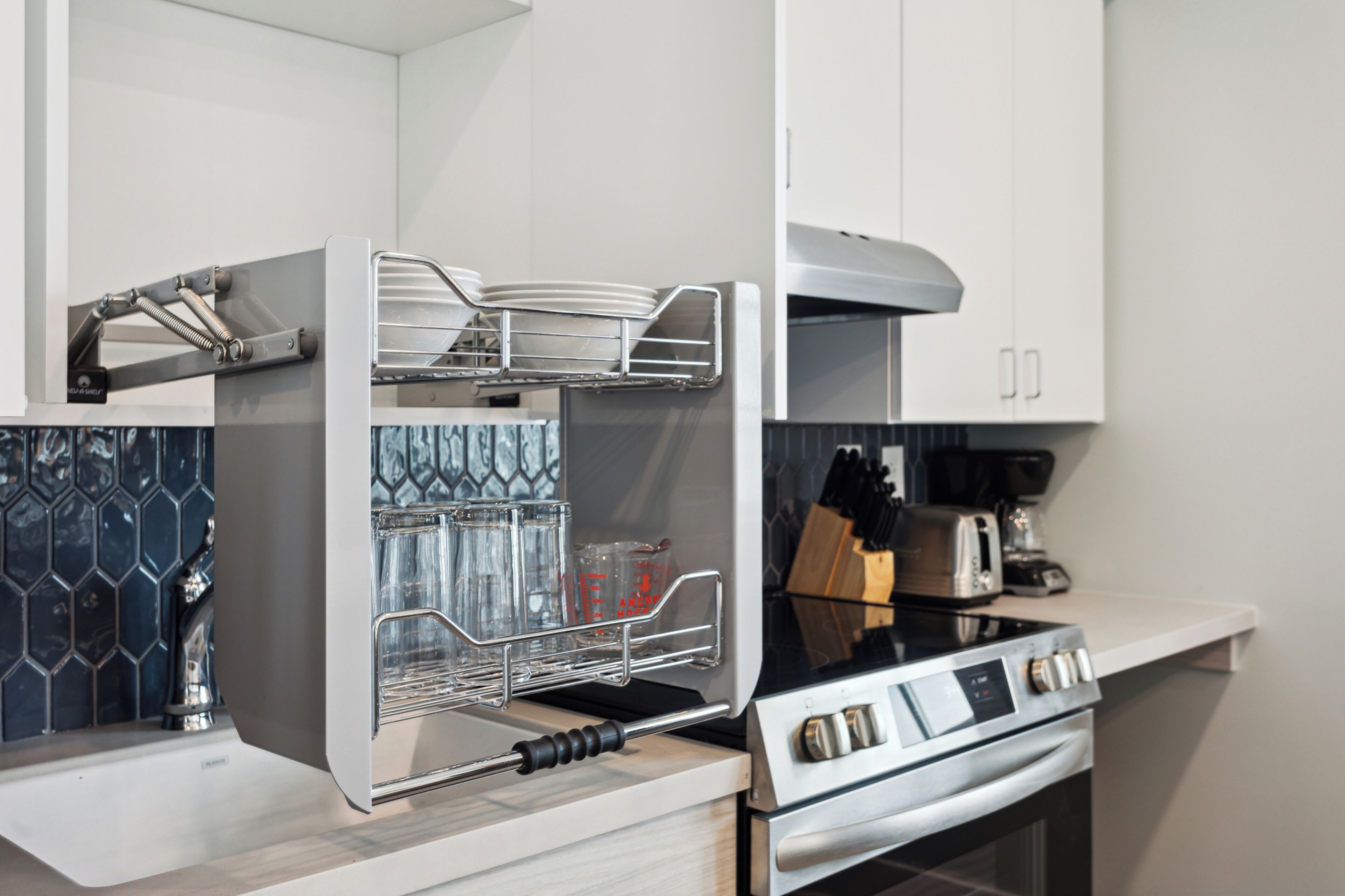 A modern kitchen with a built-in oven, a stainless steel range hood, and a dish rack.