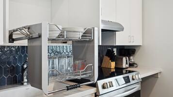 A modern kitchen with a built-in oven, a stainless steel range hood, and a dish rack.