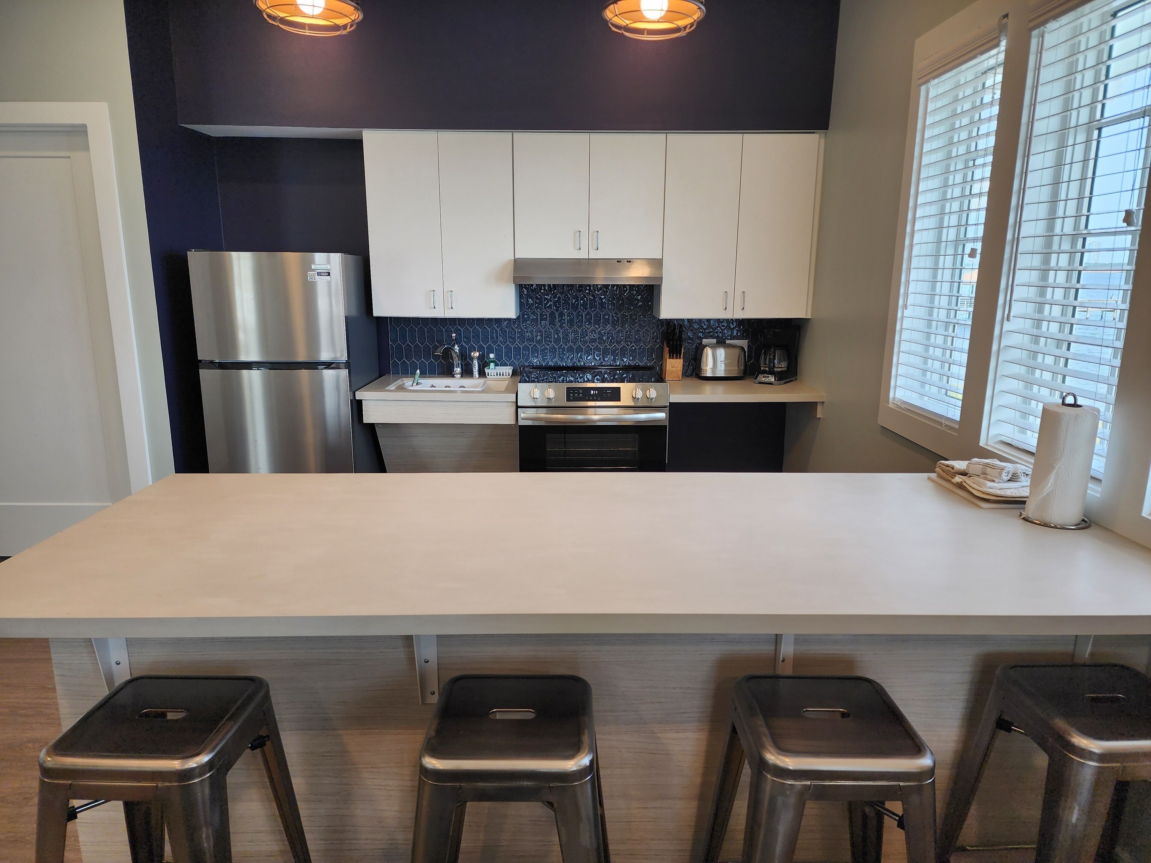 A modern kitchen with a central island, stainless steel appliances, and bar stools.