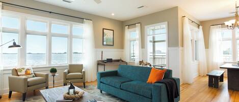 A spacious living room with a large sofa, a coffee table, and a view of the water.