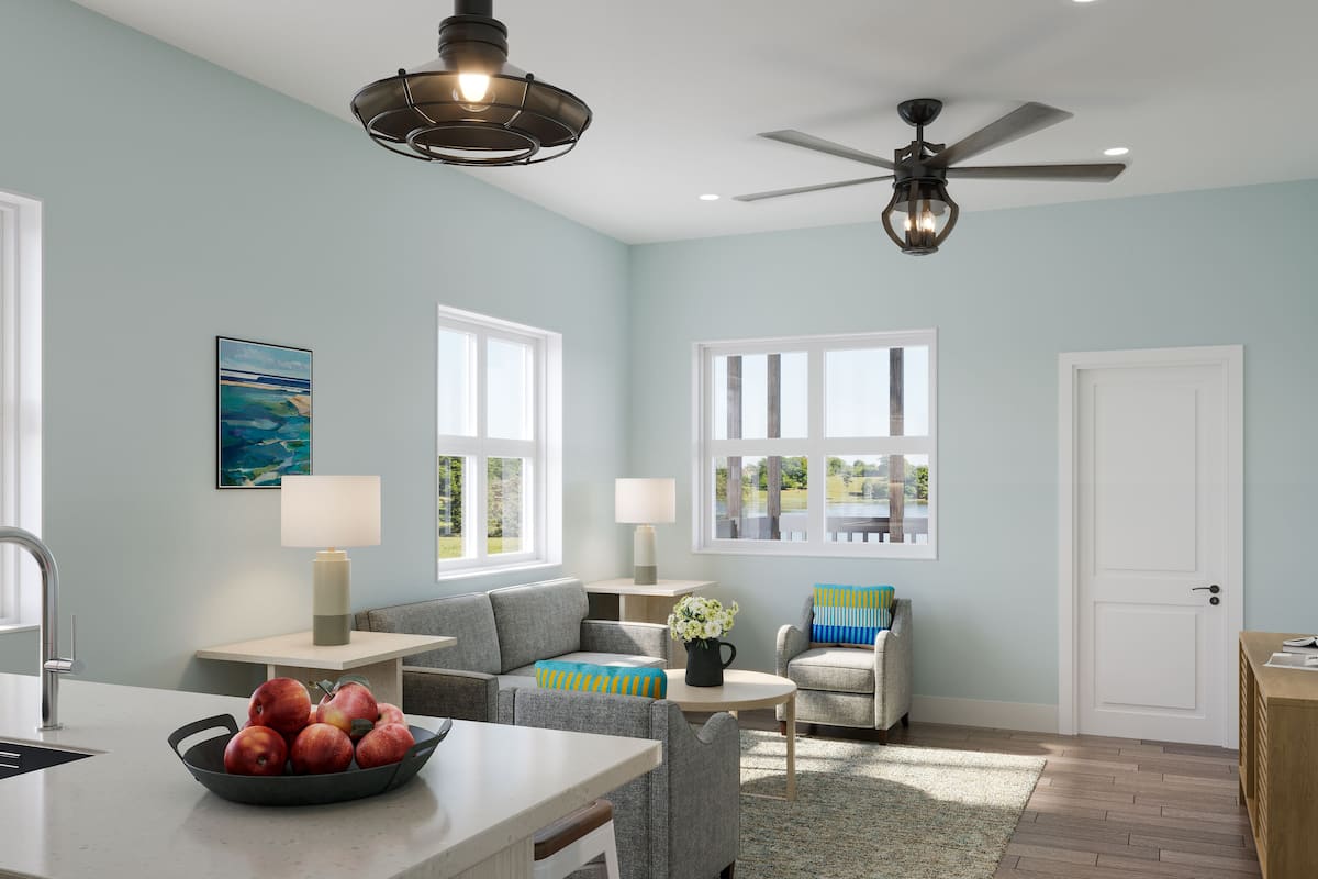 A modern living room with a kitchen area, large windows, and a ceiling fan.