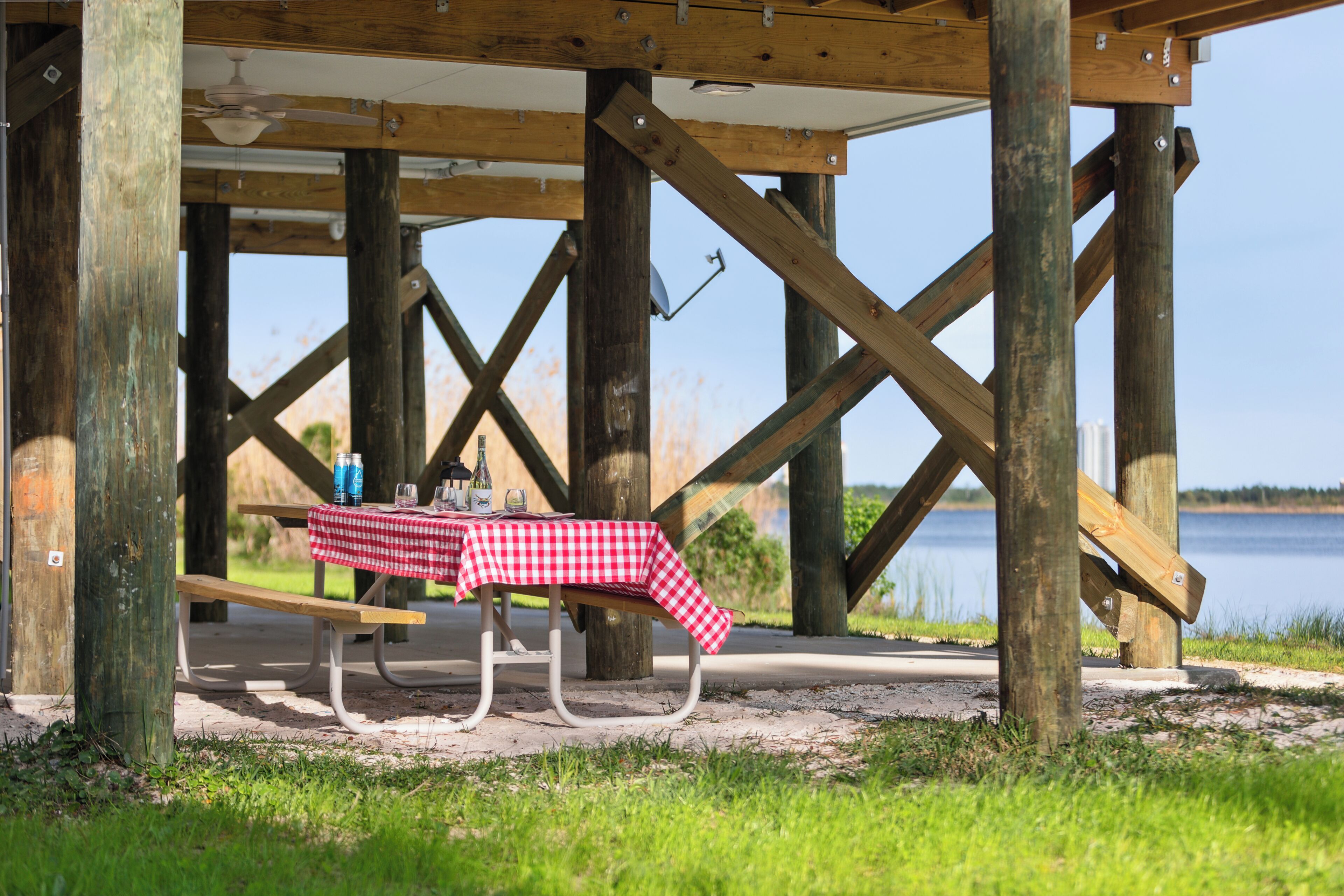 A picnic table under a wooden structure with a view of a lake.