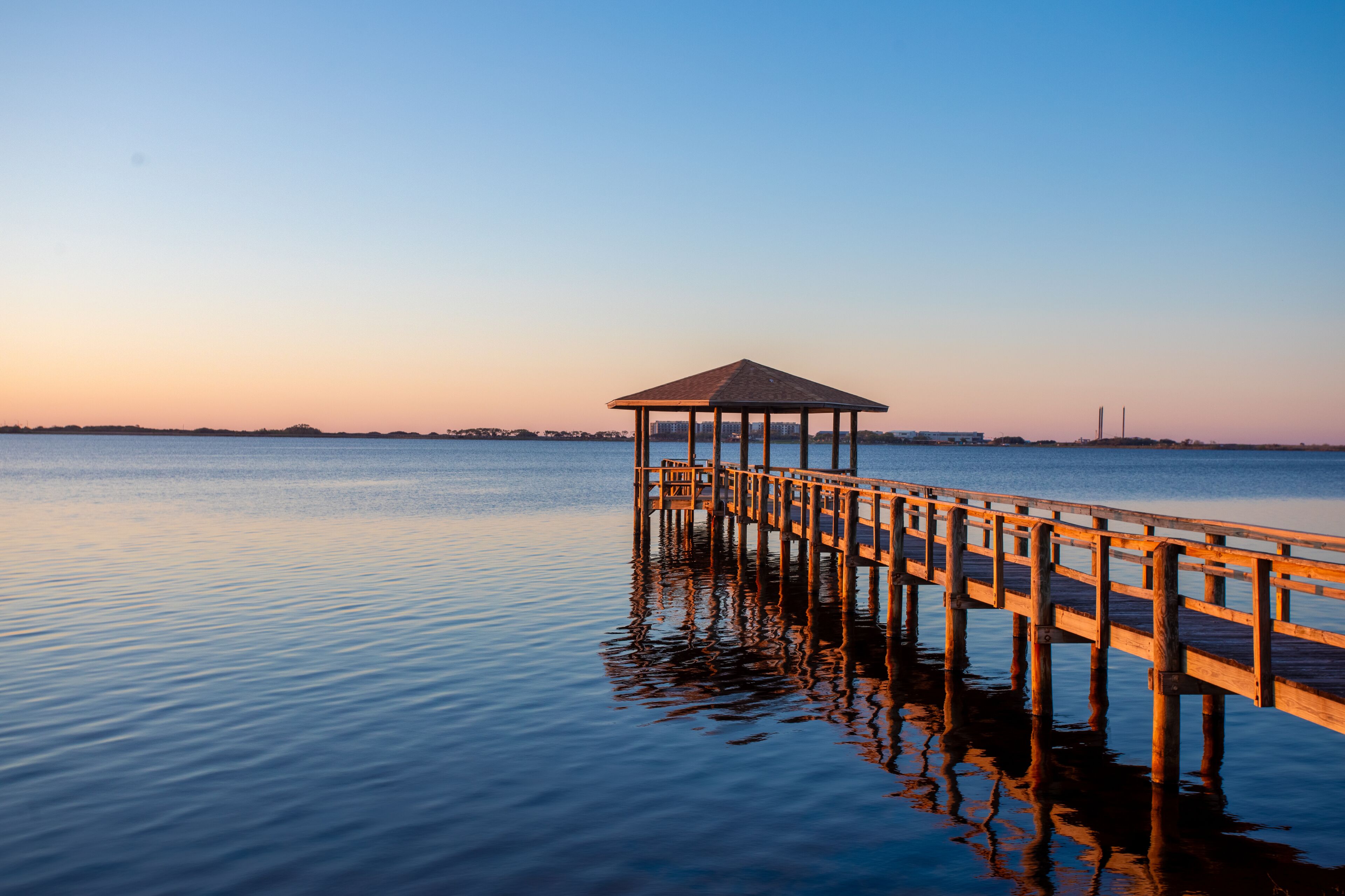 A wooden pier extending into calm water with a gazebo at the end.