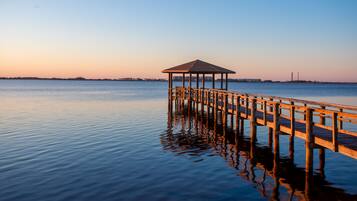 A wooden pier extending into calm water with a gazebo at the end.