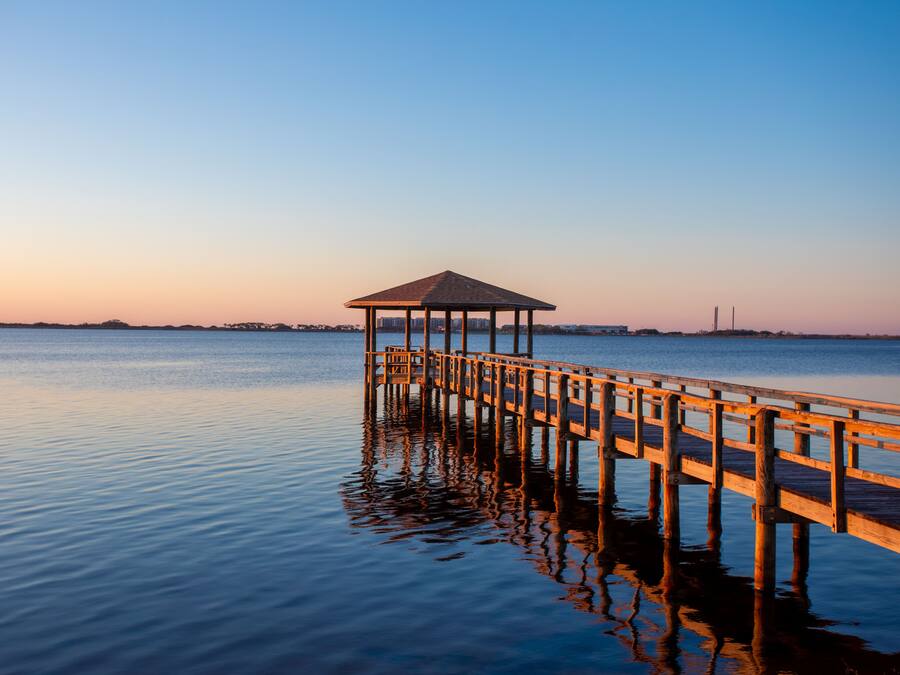 A wooden pier extending into calm water with a gazebo at the end.
