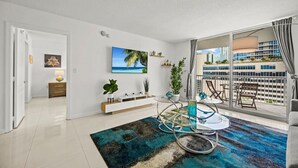 A modern living room with a glass coffee table, a blue rug, and a view of a cityscape through large windows. - Splendid Unit with Parking in Brickell Miami (Miami)