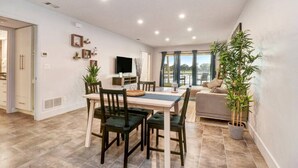 Un vaste espace de vie comprenant une table à manger, des chaises, un canapé et une grande fenêtre.