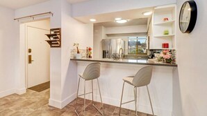 Une cuisine moderne dotée d’un coin bar, d’appareils électroménagers en acier inoxydable et d’une grande fenêtre.
