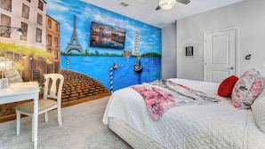 A bedroom with a mural of the Eiffel Tower and a Ferris wheel, a bed with a quilted cover, a white chair, and a desk with a lamp. - NEW 9Bdrm Themed w Arcade near Disney & Universal (Kissimmee)