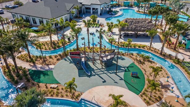 A resort with a large swimming pool, palm trees, and a building with a covered area. - NEW 9Bdrm Themed w Arcade near Disney & Universal (Kissimmee)
