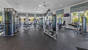 A modern gym with various exercise equipment, large windows, and a ceiling with recessed lighting. - NEW 9Bdrm Themed w Arcade near Disney & Universal (Kissimmee)