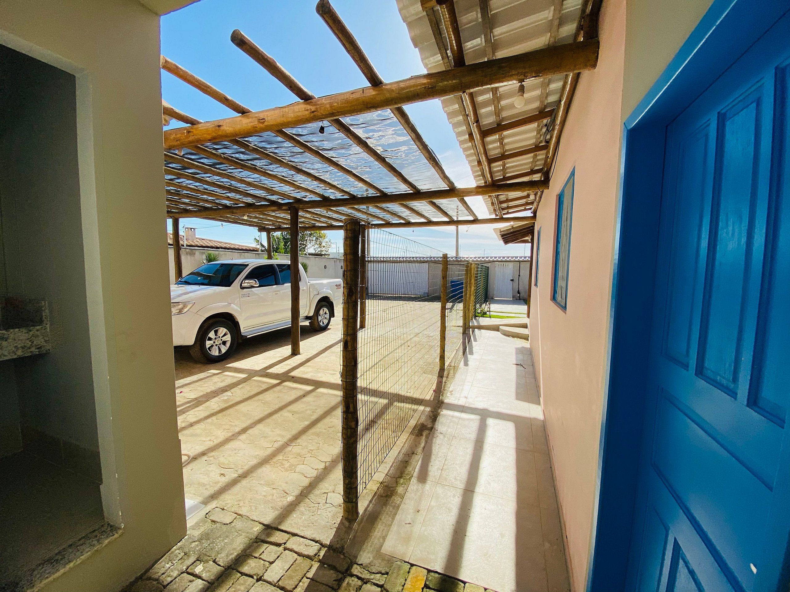 A covered outdoor area with a car parked, a blue door, and a metal roof structure.