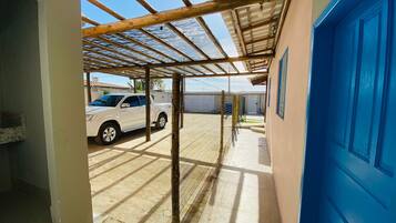 A covered outdoor area with a car parked, a blue door, and a metal roof structure.
