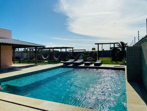 Relax in the backyard with a rectangular pool, lounge chairs, and a hammock.