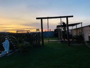 A garden with a statue, a swing set, and a pergola. - Casa Marataizes (Marataizes)