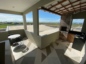 A balcony with a table and chairs, a kitchen area with a sink, and a view of the countryside. - Casa Marataizes (Marataizes)