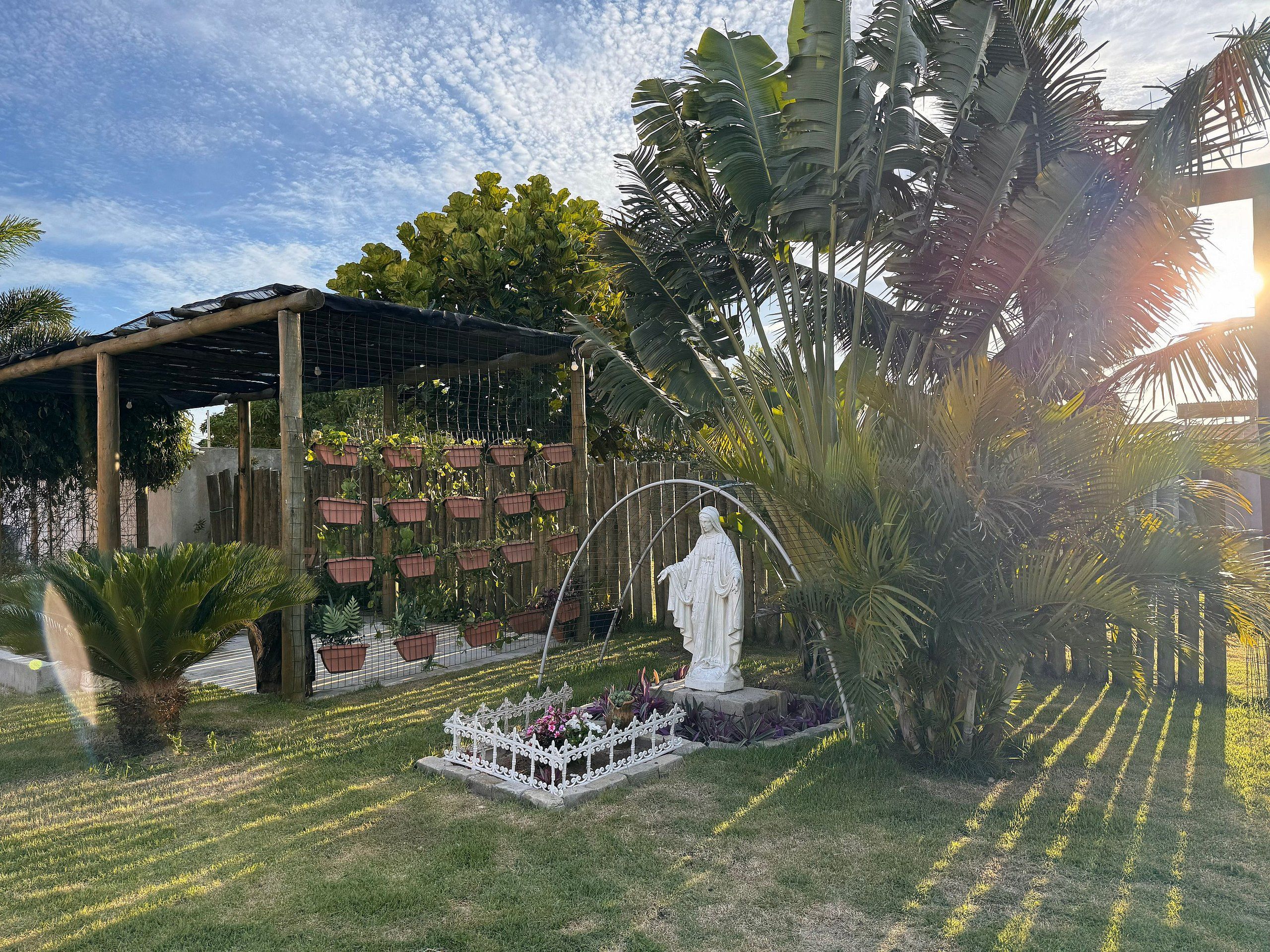 Um jardim com uma estátua, vasos de plantas e uma estrutura de pérgula.