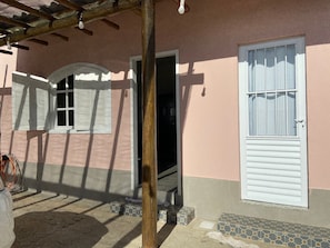 A building with a pink exterior, white doors, and windows with shutters. There are steps leading to the entrance, and a wooden structure above. - Casa Marataizes (Marataizes)