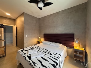 A bedroom with a bed, a ceiling fan, a nightstand with a lamp, and a wardrobe. - Casa Marataizes (Marataizes)