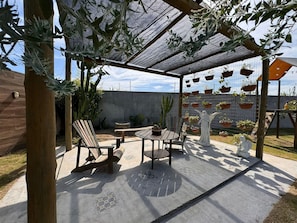 A covered patio area with wooden furniture, a statue, and hanging planters. - Casa Marataizes (Marataizes)
