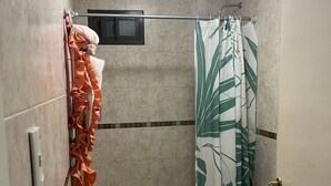 Ein Badezimmer mit Dusche, zwei Toiletten und einem Handtuchhalter mit einem orangefarbenen Handtuch.