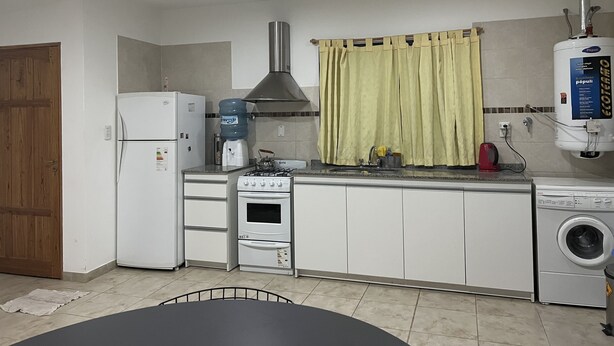 Eine kompakte Küche mit Kühlschrank, Herd, Backofen, Spüle und Waschmaschine.