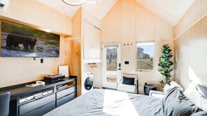 Un dormitorio moderno con una cama grande, un televisor de pantalla plana, lavadora y vistas al exterior.