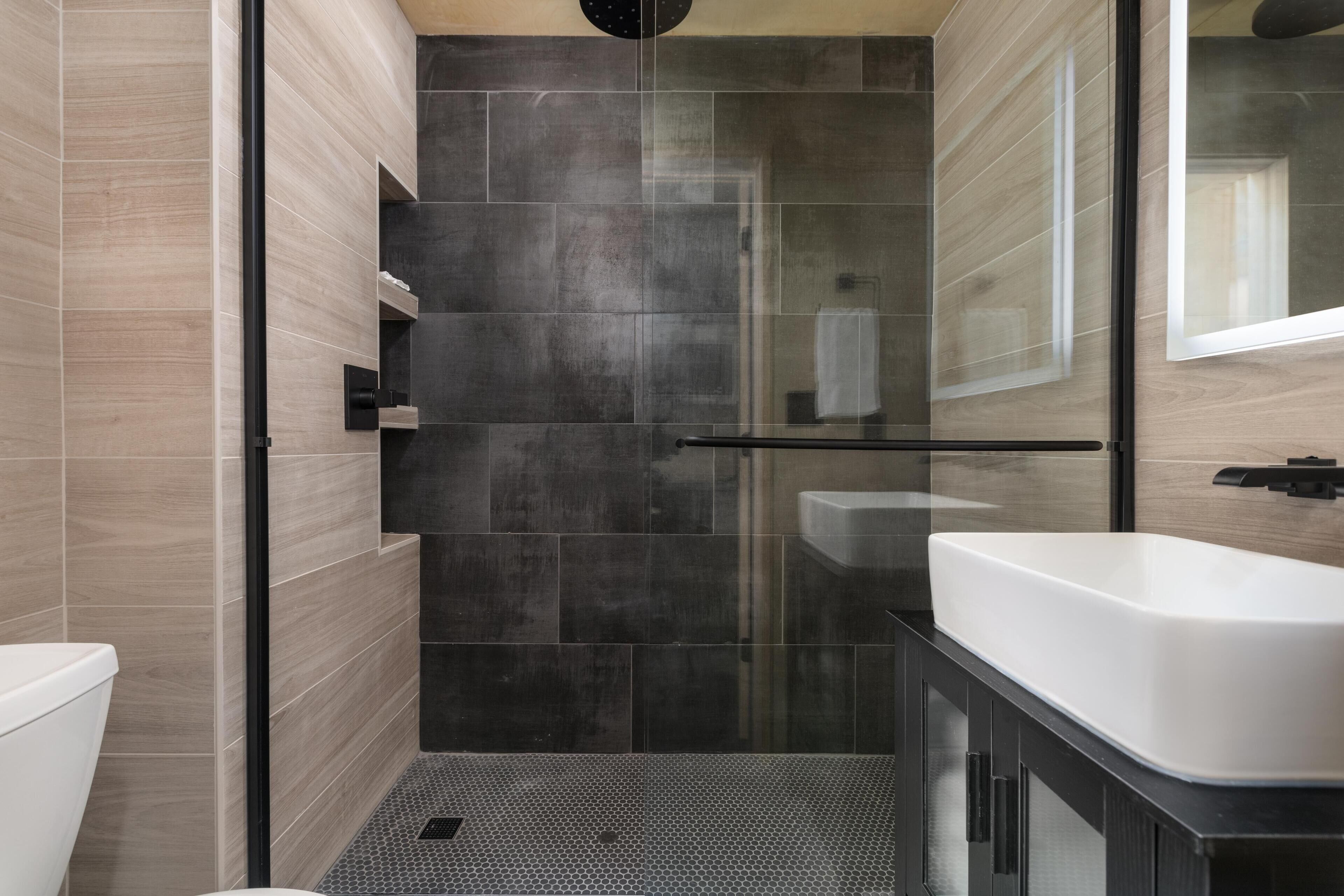 A modern bathroom with a shower, toilet, and sink.