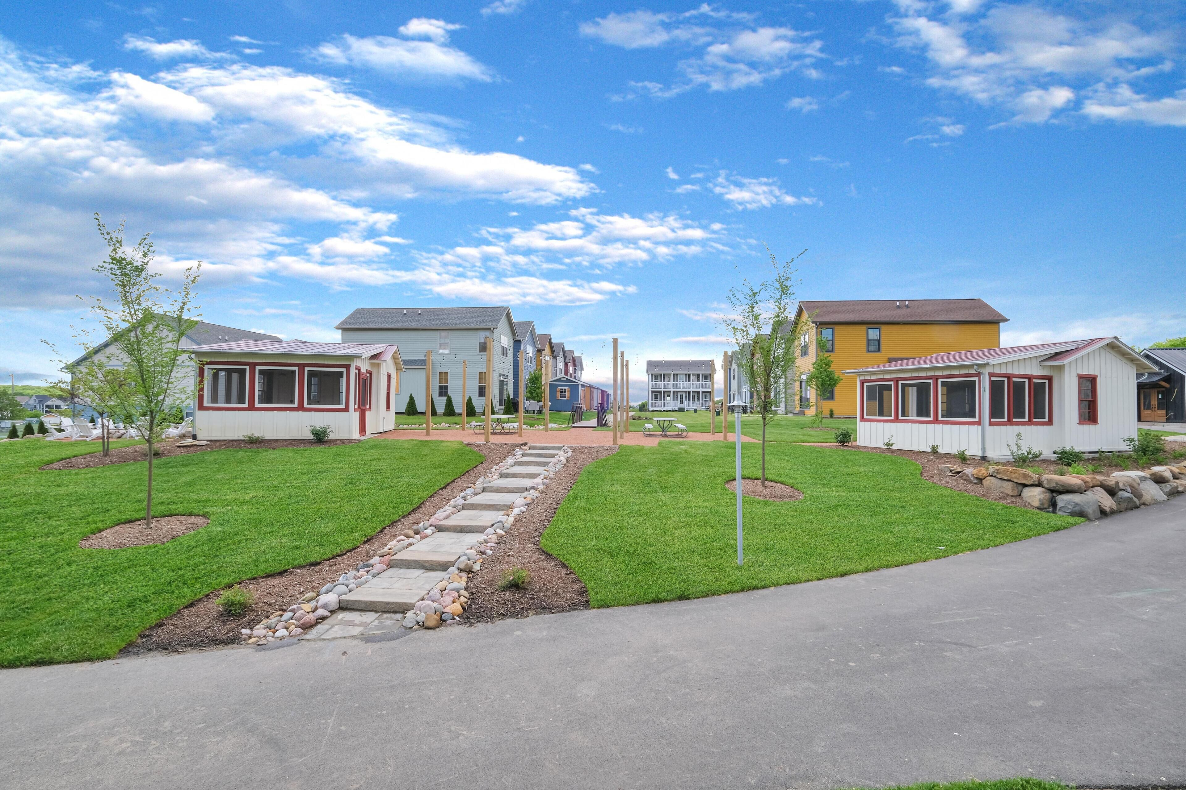 A residential area with a row of houses, a central pathway, and a well-maintained lawn.