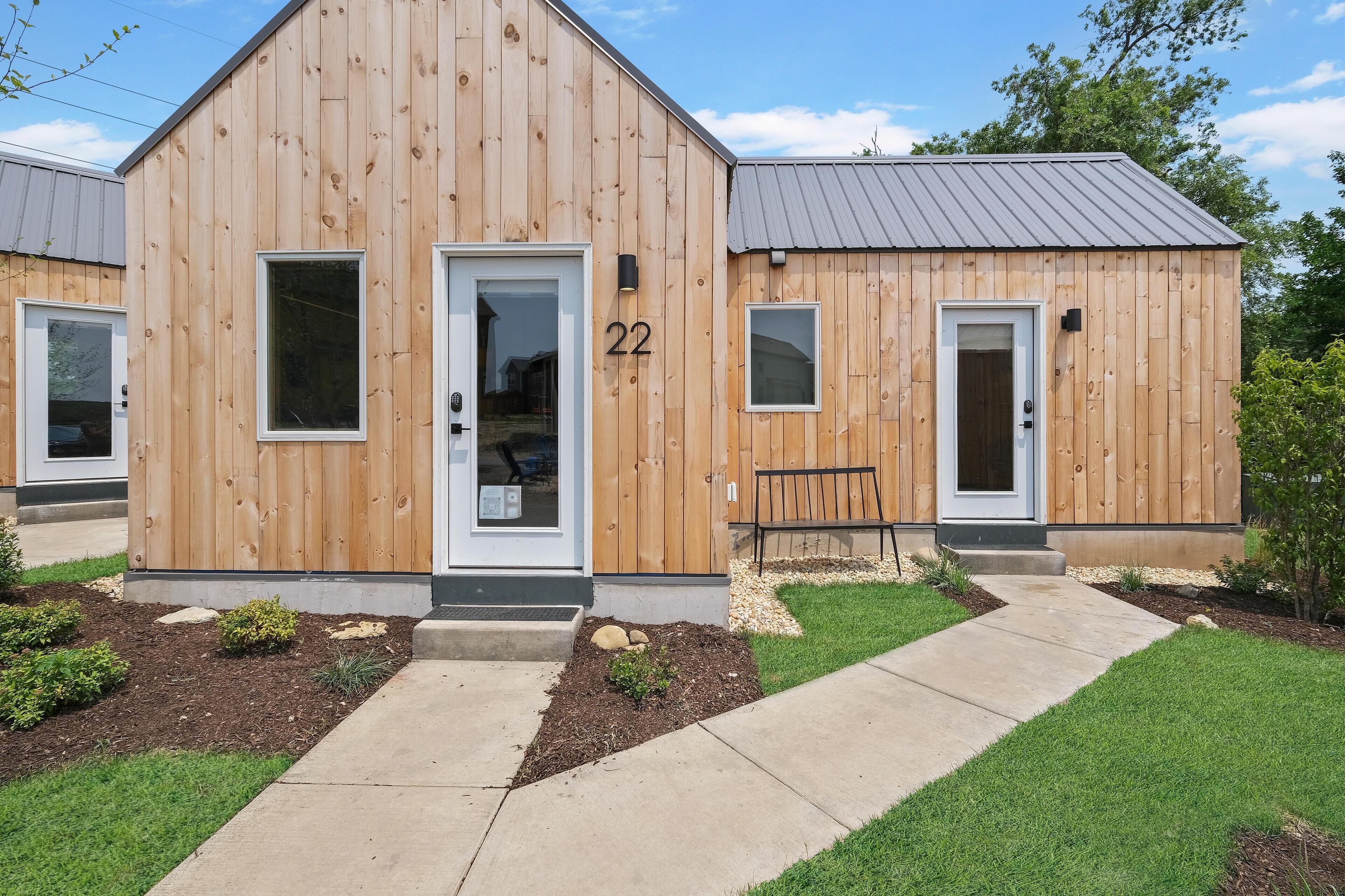A wooden building with a number '22' on the door, a bench outside, and a well-maintained lawn.