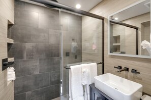 Een moderne badkamer met een douchecabine van glas, een wit wastafelmeubel en een grote spiegel.