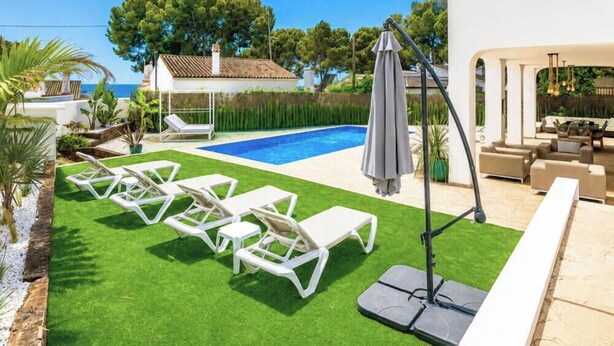 A pool with sun loungers, a covered seating area, and a view of the sea. - Villa Milana • Sea views & Beach vibes (Moraira)